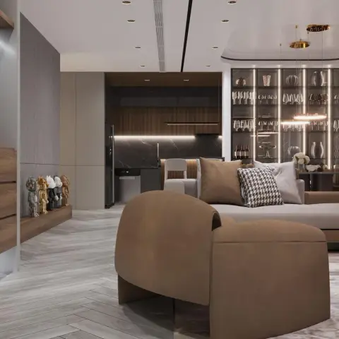 Render of an open-plan living room with a curved tan bouclé armchair and sectional sofa facing a backlit glass bar display wall, herringbone wood flooring