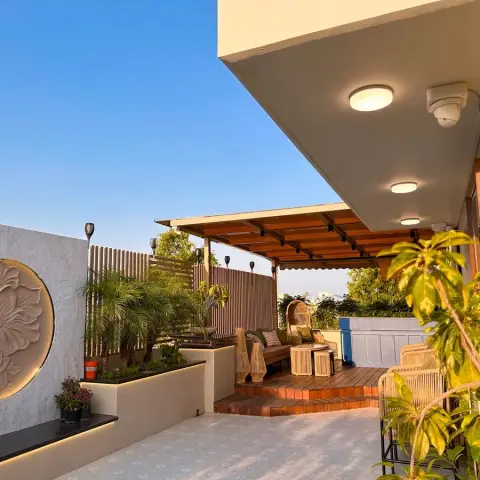 Rooftop terrace in late sun - a carved lotus medallion sunk into a backlit circular recess on the grey boundary wall