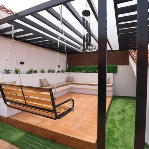 Rooftop terrace with a black-framed pergola over a wood-decked seating area, a hanging wooden bench swing