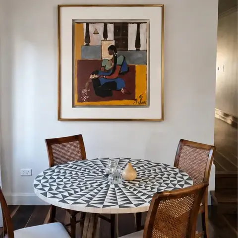 Round dining table with a radiating black-and-white marble inlay top and cane-back teak chairs