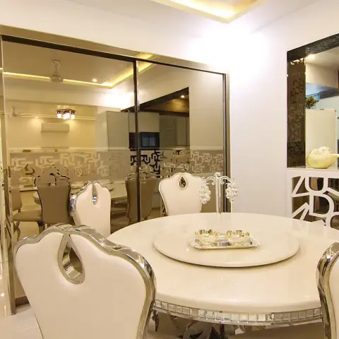 Round marble dining table with ornate cream leather and polished-chrome wingback dining chairs