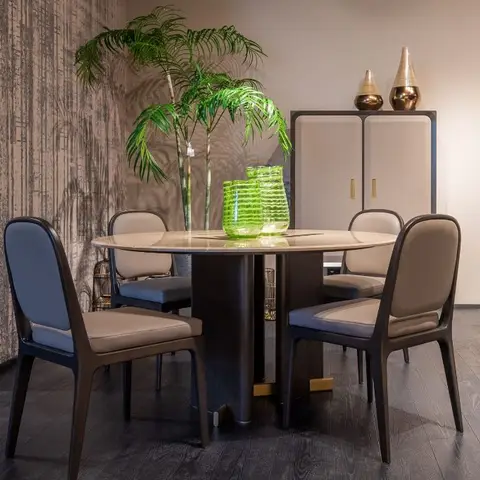 Round marble-top dining table with four leather-and-fabric chairs against a textured bronze wallpaper wall