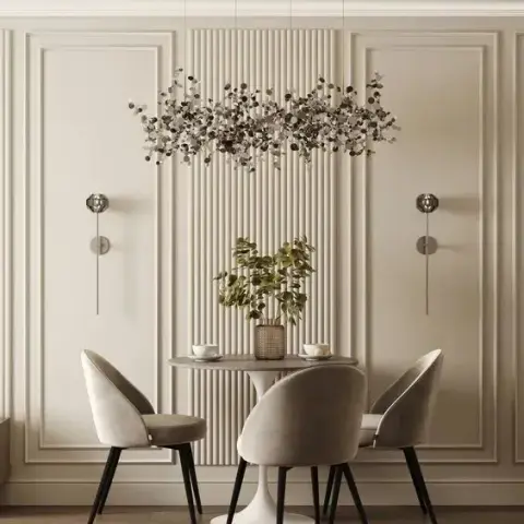 Round pedestal dining table with grey velvet chairs beneath a branch-style leaf chandelier