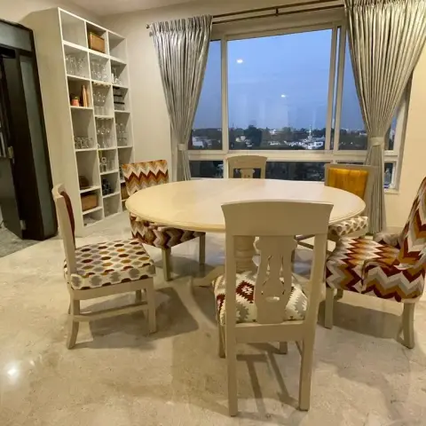 Round whitewashed dining table with five mismatched chairs upholstered in red-and-ochre chevron and kilim fabrics