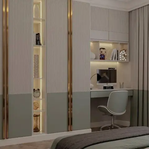 Sage-and-ivory wardrobe wall with brass inlay strips and a lit vertical niche, running into a built-in desk where a superhero figure and a light-up unicorn