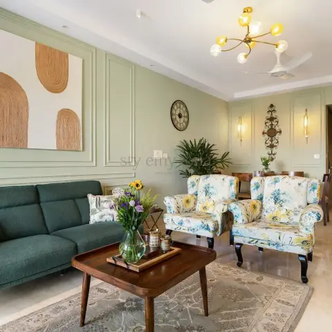 Sage-green moulded wall behind a bottle-green three-seater, faced by two floral wingback chairs