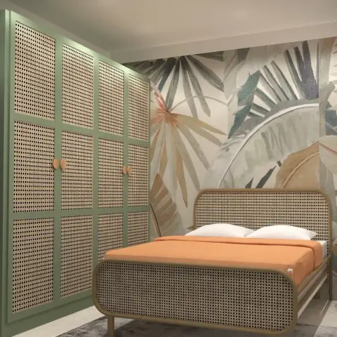 Sage-green wardrobe run with cane-webbed shutter panels facing a rattan bed dressed in terracotta