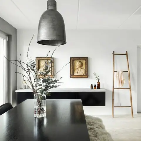 Scandinavian dining nook with a black wood table, an oversized concrete-look pendant light, a floating black console