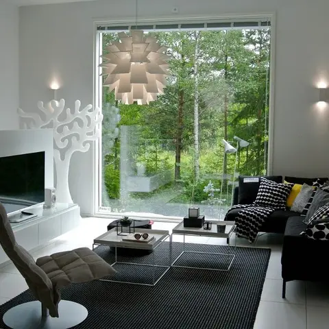 Scandinavian living room with a statement folded-panel pendant light, a black sectional styled with graphic monochrome cushions