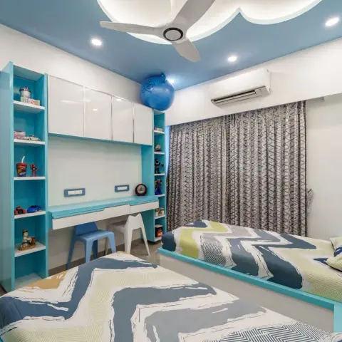 Shared children's room with two turquoise-and-white built-in beds in wave-print bedding, a twin study counter with small blue and white stools