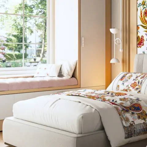 Single bed dressed in a paisley throw beside a blush-tufted window seat built over drawers