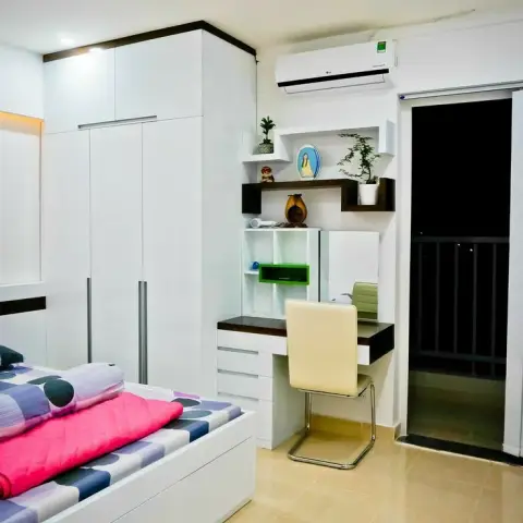 Single-bed room with a white box-storage bed under a purple-and-pink dotted spread, a white wardrobe with loft