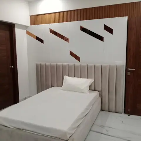 Single bed with a full-width channel-fluted beige velvet headboard against a white panelled wall inlaid with diagonal rose-gold strips