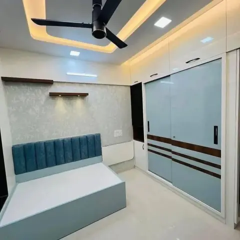 Single storage bed with a teal channel-tufted headboard under two spot-lit walnut floating shelves