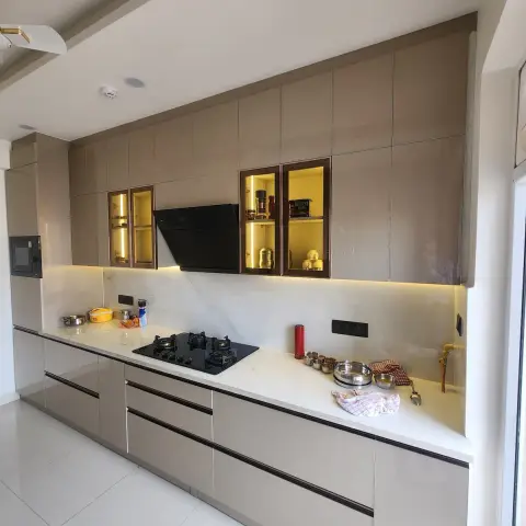 Single-wall taupe high-gloss kitchen with a white quartz counter under a full-height marble slab dado