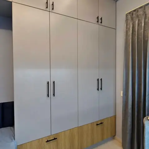 Site photo of a floor-to-ceiling four-shutter wardrobe in white laminate sitting on an oak-finish drawer plinth