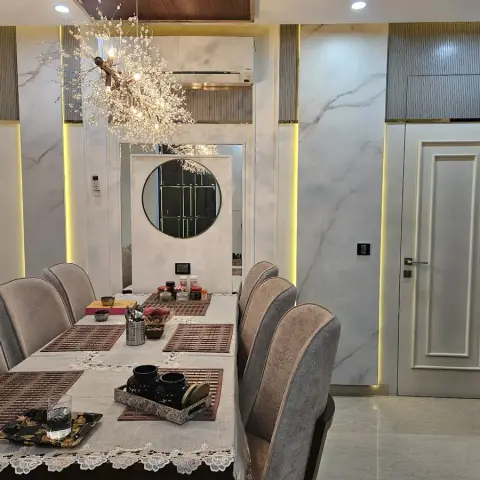 Six-seat dining table with grey fan-back chairs under a branching crystal sputnik chandelier
