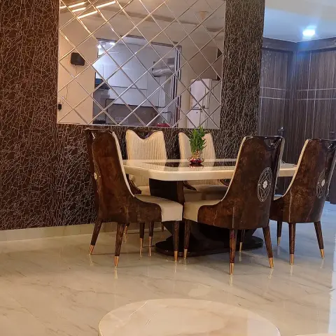 Six-seater dining set in burl-print leatherette chairs with brass-tipped legs around a cream marble table