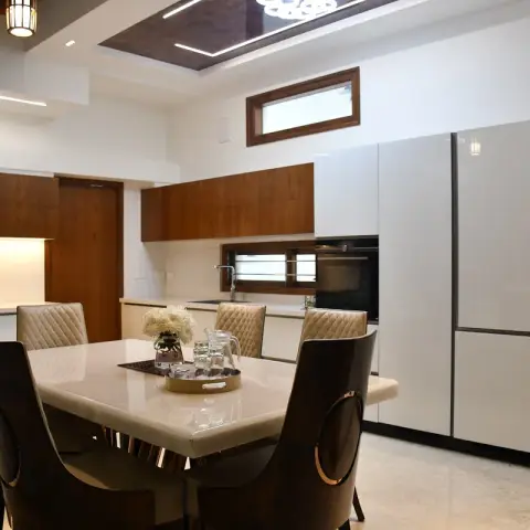 Six-seater marble-top dining table with quilted cream and dark leatherette chairs in the foreground