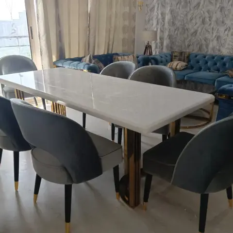 Six-seater white marble dining table on a mirror-gold pedestal base with grey velvet chairs