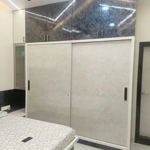 Sliding wardrobe in grey stone-effect laminate with high-gloss dark marble-print loft shutters above and a louvred service hatch beside it