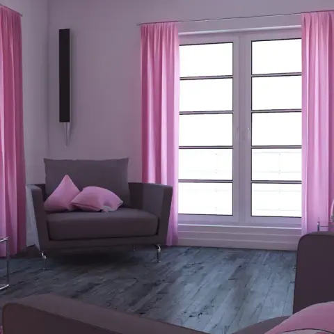 Small living room with grey armchairs, floor-length pink curtains either side of a balcony door, and a pink accent pillow