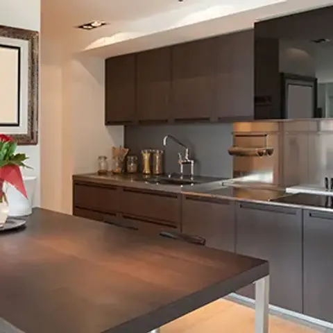 Small low-resolution shot of a wenge-and-stainless galley kitchen with a full-height steel splashback