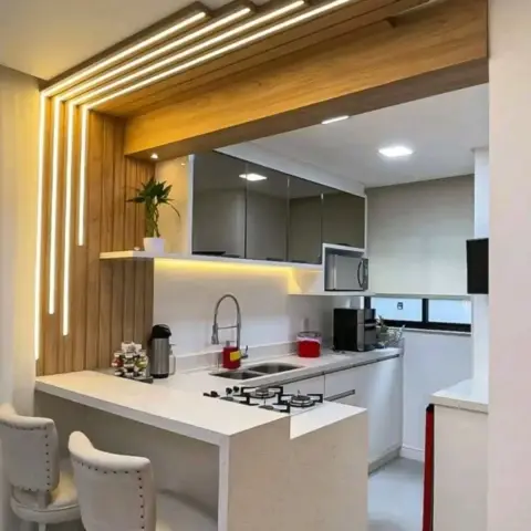 Small open kitchen framed by a wooden portal of staggered battens with recessed linear LEDs