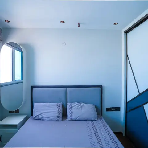 Small spare bedroom shot under a heavy blue cast - twin-panel upholstered headboard
