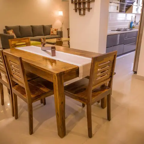 Solid sheesham four-seater with slat-back chairs and a cream table runner in the foreground