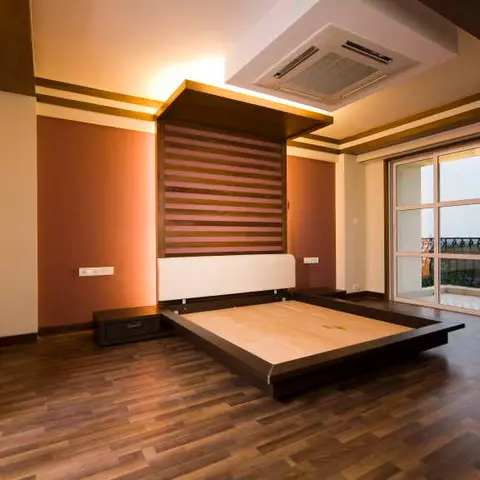 Spacious bedroom with a floating platform bed and wood-slat headboard canopy against a terracotta accent wall, dark wood flooring