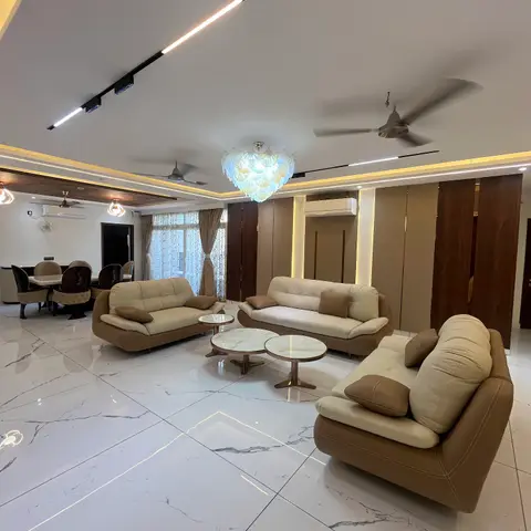Spacious living room with three cream leather sofas around nesting marble coffee tables on glossy book-matched marble flooring