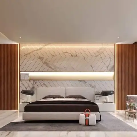 Statuario marble headboard wall scored with diagonal brass inlay lines and split by a lit horizontal slot