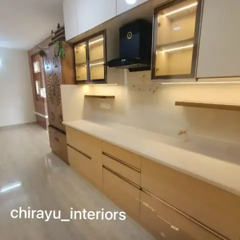 Straight-line beige high-gloss kitchen with gola-profile handles and LED-lit glass wall cabinets