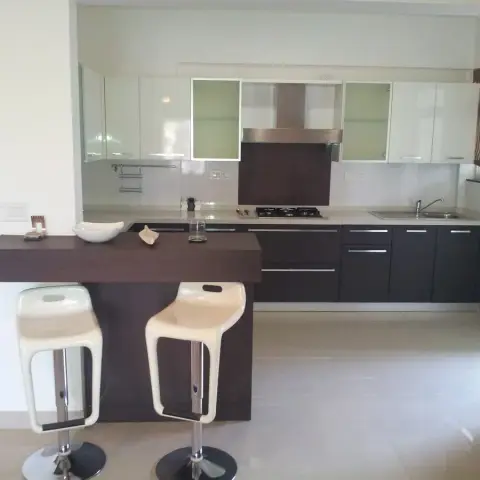 Straight-run modular kitchen closed off by a wenge-laminate breakfast ledge with two white moulded gas-lift stools