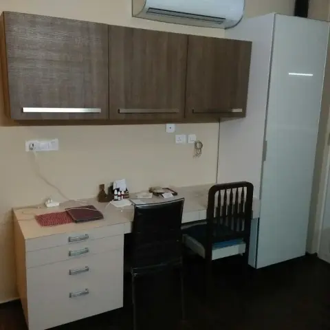 Study desk with overhead brown laminate cabinets, a four-drawer pedestal below, and a tall glossy wardrobe alongside, under a wall-mounted split AC.