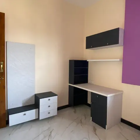 Study nook with a black-and-white desk unit, overhead cabinet and open box shelving against a bold purple accent wall.