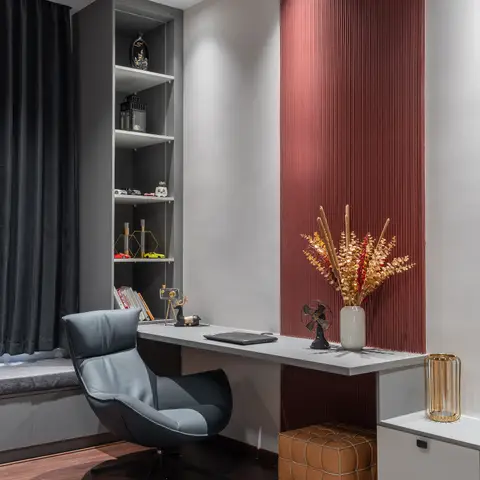 Study nook with a floating white desk against a rust-red fluted panel wall, a grey open bookshelf, and a charcoal leather swivel chair.