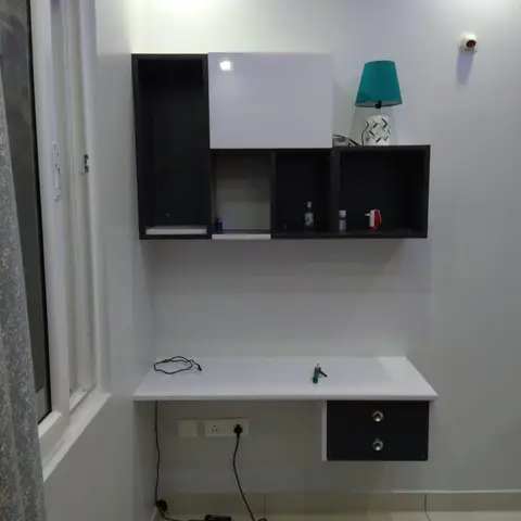 Study nook with a floating white-and-black desk and matching wall-mounted storage cubbies, cables still exposed beneath the desk.