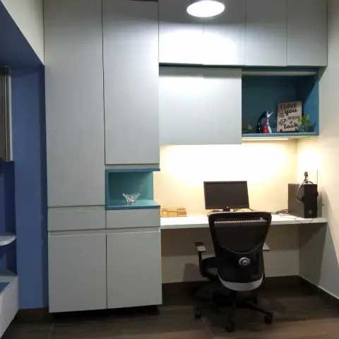Study nook with a floor-to-ceiling white wardrobe, teal-backed open display niches holding decor pieces, and a built-in desk lit by a pendant lamp.