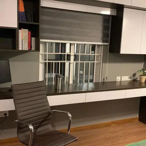 Study nook with a grey-and-white laminate desk, black leather office chair, overhead bookshelf and loft wardrobe, wood-look flooring