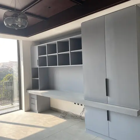 Study nook with a matte-grey built-in desk, cubby shelving and a tall adjoining wardrobe, under a dark coffered ceiling with a glass pendant light.