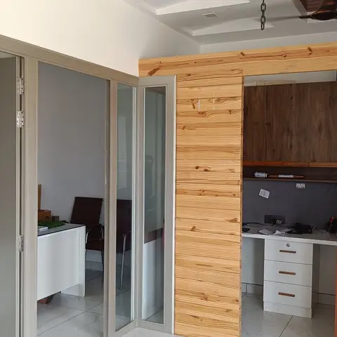 Study nook with a wood-plank clad pillar beside a built-in desk with overhead wood cabinets and a white drawer unit