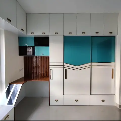 Study nook with a wood-slat feature wall behind an L-shaped desk, beside a turquoise-and-white sliding-door wardrobe with brass trim.