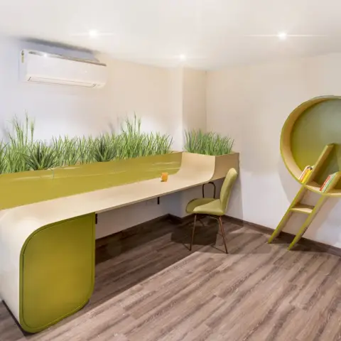 Study with a long curved olive-green and birch desk running the length of the wall under a continuous strip of tall artificial grass