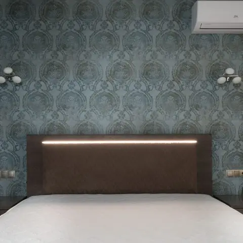 Symmetric bed wall with damask-pattern wallpaper, matching brass wall sconces either side
