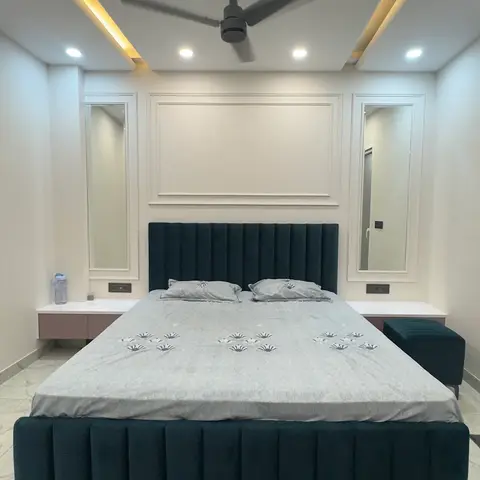 Symmetric bedroom with a dark teal channel-tufted bed and matching bench, flanked by twin arched mirrors around a moulded wall panel