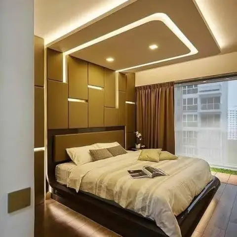 Tan block-panelled headboard wall inlaid with recessed LED slots, under a curved cove-lit false ceiling