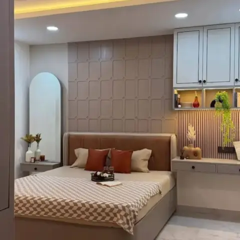 Tan channel-leather headboard against a beige grid-moulded wall, an arched mirror over a floating bedside console on the left and a dresser run on the right