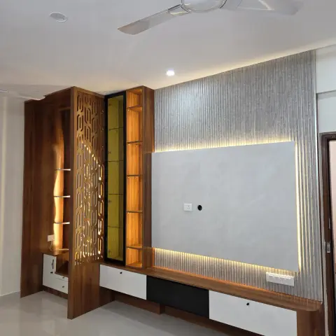 Teak-and-white TV wall where a backlit grey stone panel is framed by fluted concrete-look battens